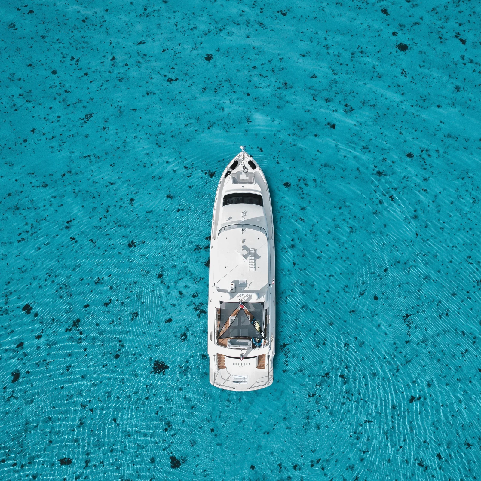 Vue aérienne d’un bateau à moteur blanc au mouillage dans une eau turquoise